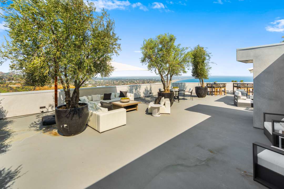 White outdoor furniture with large potted trees