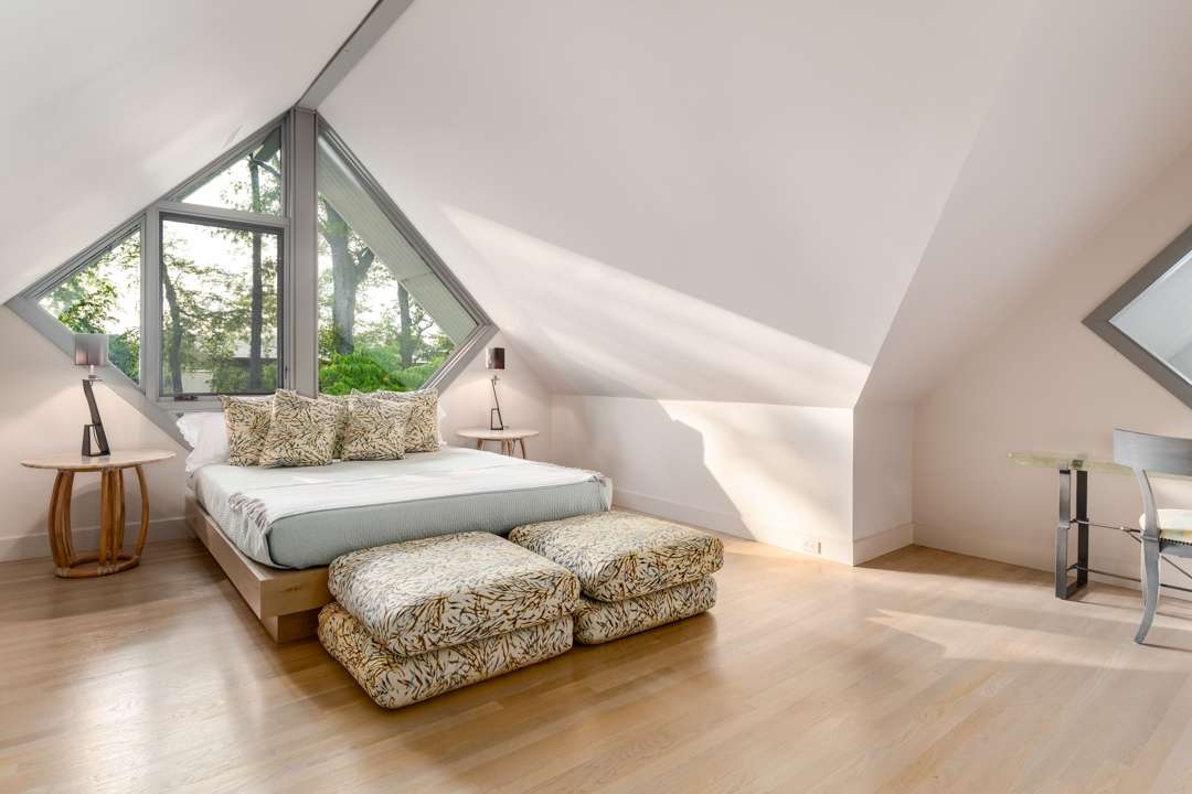 Bedroom with diamond window and nature pillows and ottomans