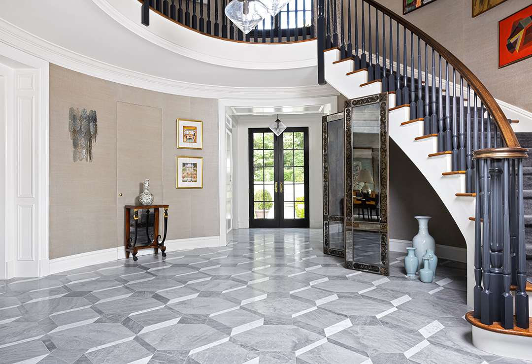 Foyer with grey marble floors and black stairs