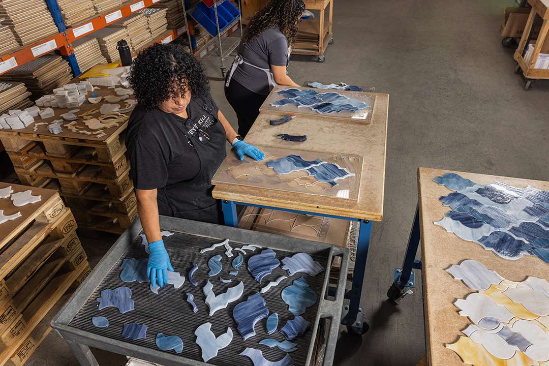 Hand laying a waterjet cut glass mosaic into trays in preparation for mesh mounting.