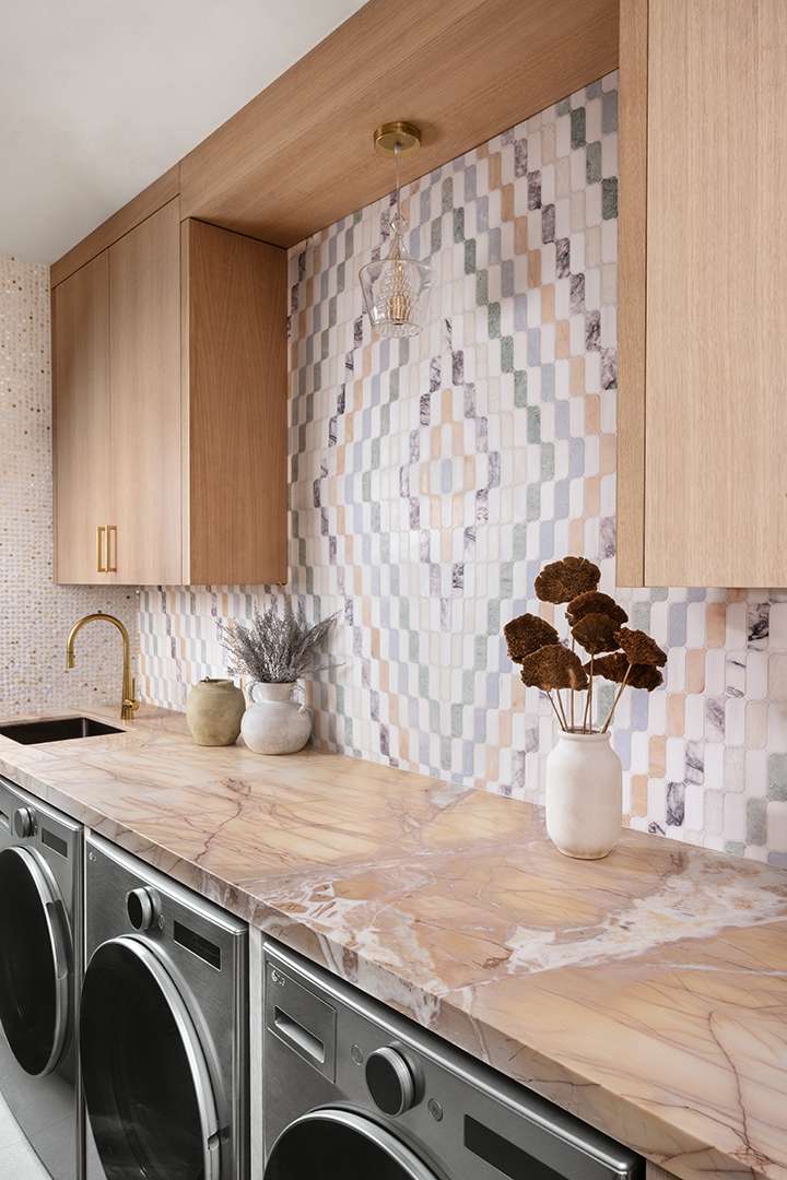 Laundry room with marble counter and colorful backsplash