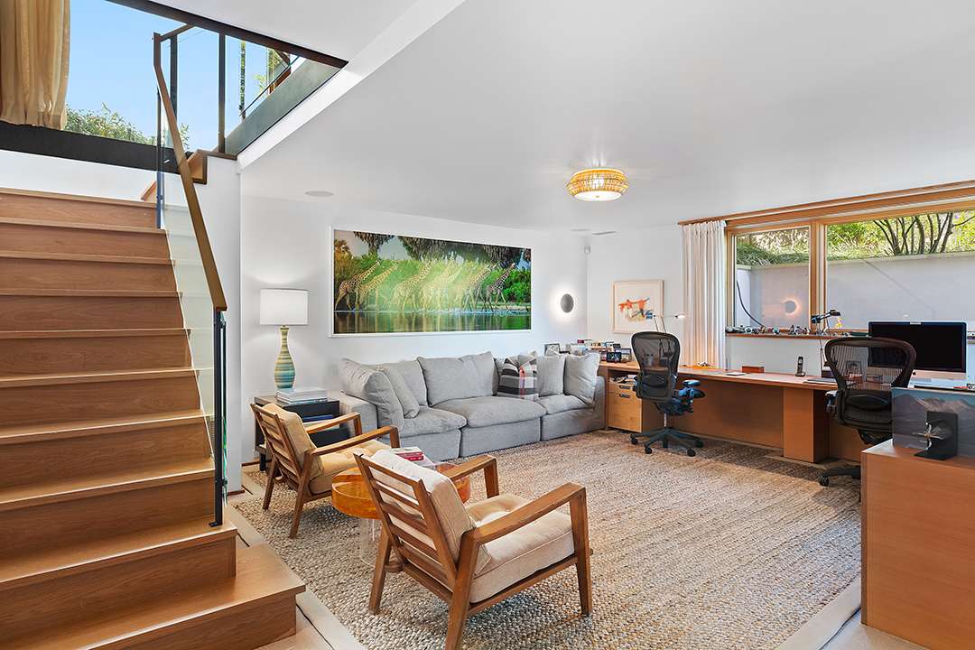 Office with wood desks and chairs and a grey couch