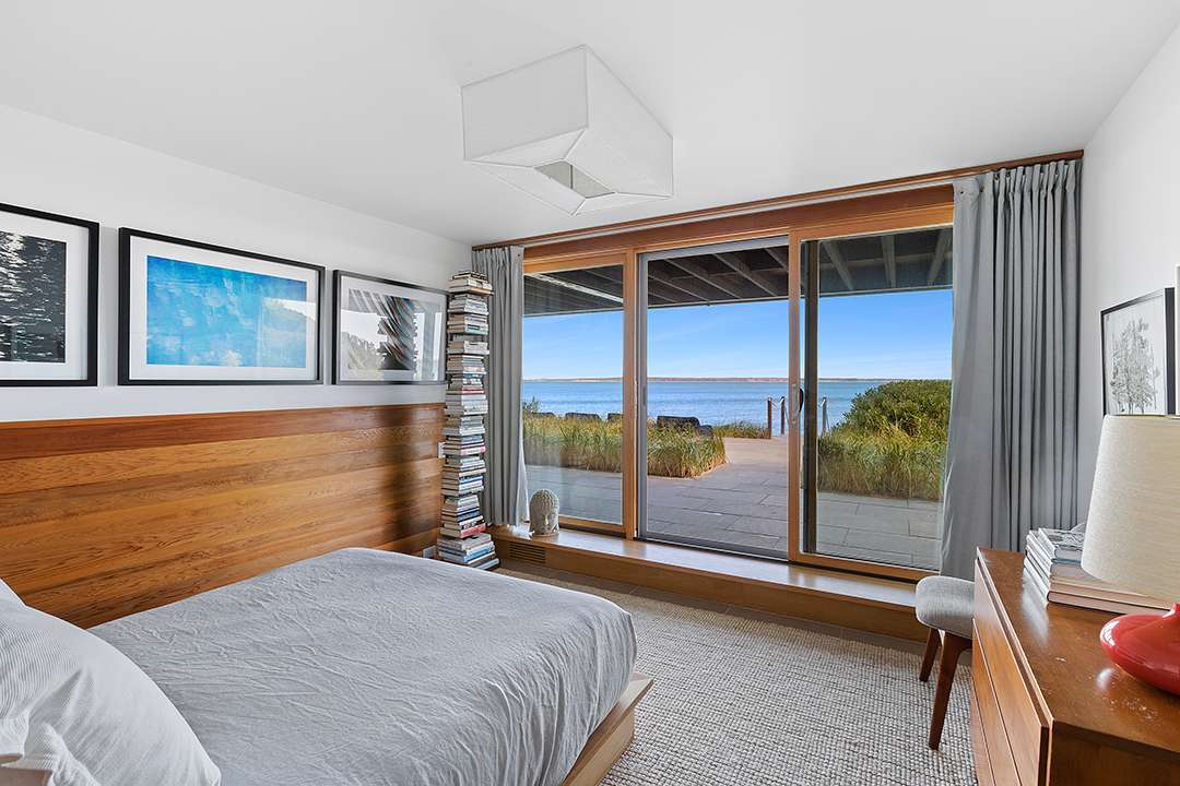 Wood based bedroom with grey bedding overlooking the bay