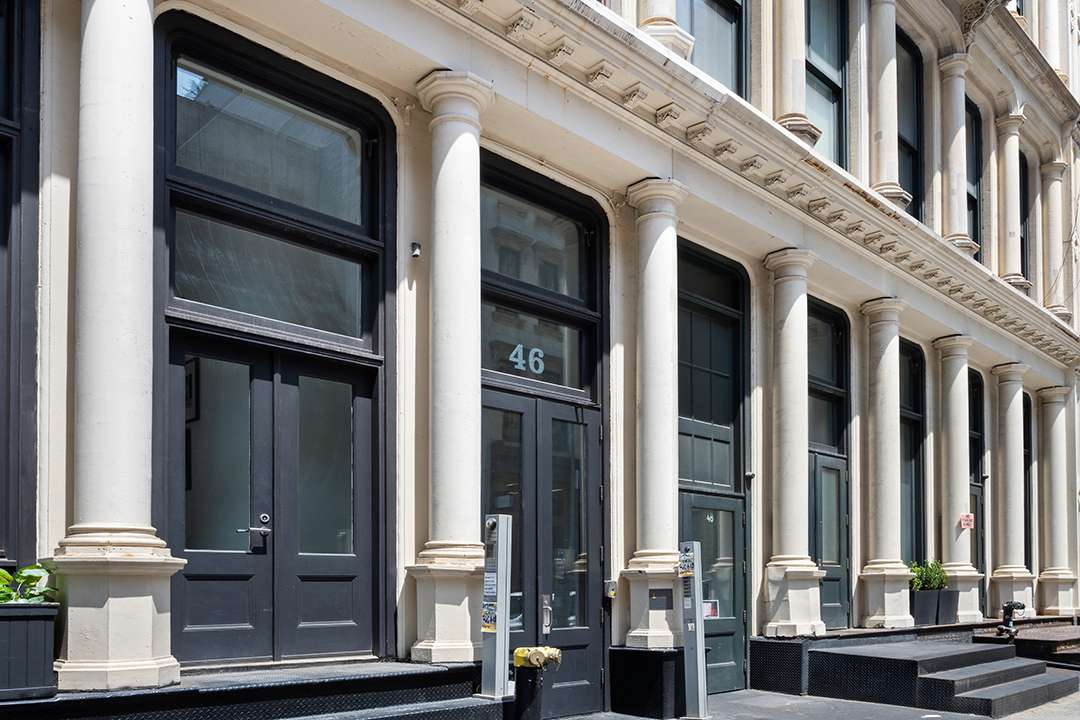 Outside Tribeca triplex with white pillars and black doors and steps