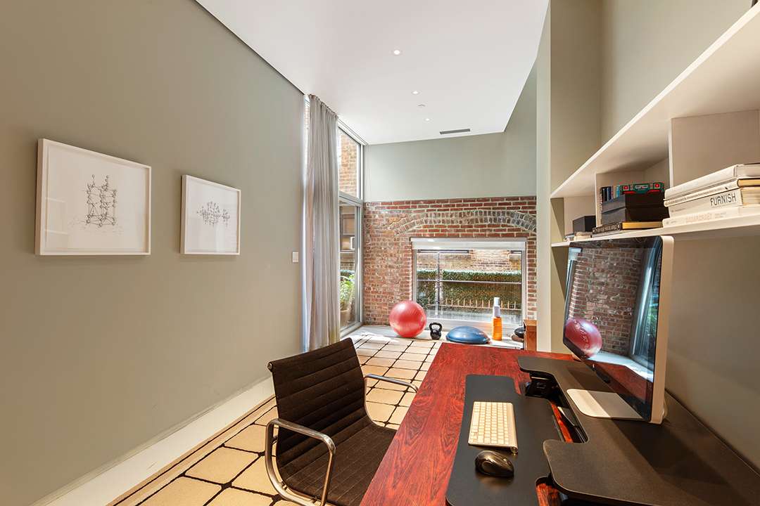 Office with red wood table and black velvet chair with space for exercise equipment